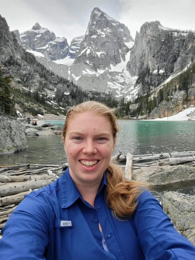 Grand Tetons elopement photographer Lucy Schultz smiles at the camera on a hike at Delta Lake.