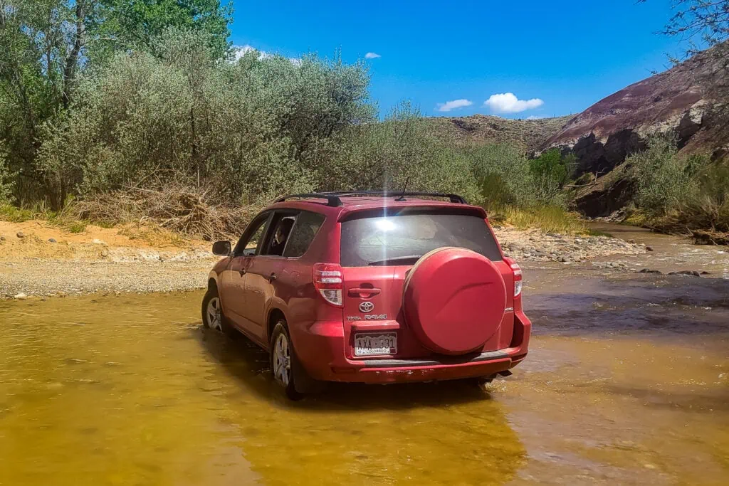 A vehicle fording the river in Capitol Reef National Park on a road trip.