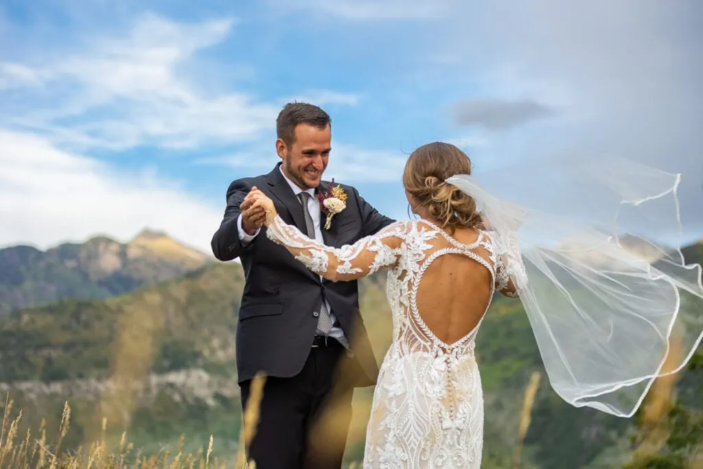 A groom embraces his bride as her veil blows in the breeze in Marble, Colorado.