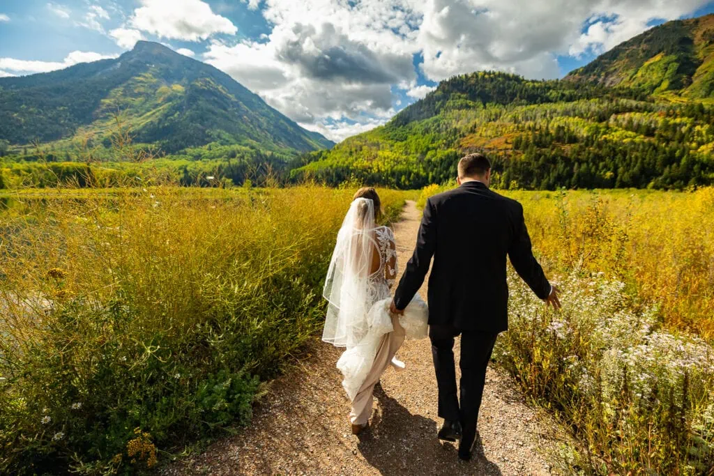 An elopement couple walks to their ceremony spot in Marble, Colorado at Beaver Lake.