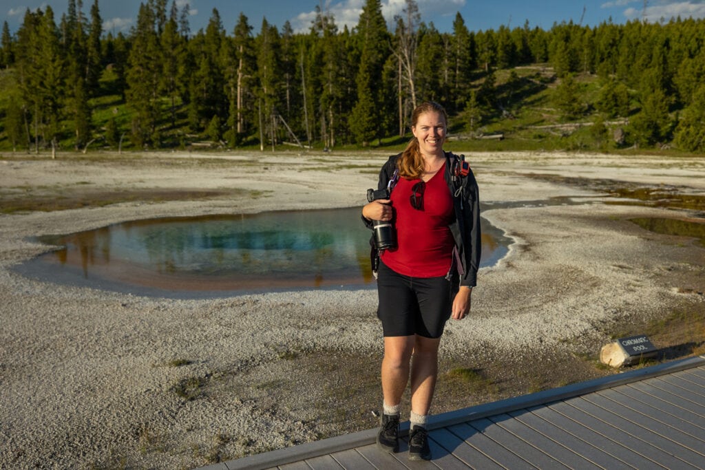 Photographer Lucy Schultz is shown here wearing a red shirt in Yellowstone National Park at the beauty pool.